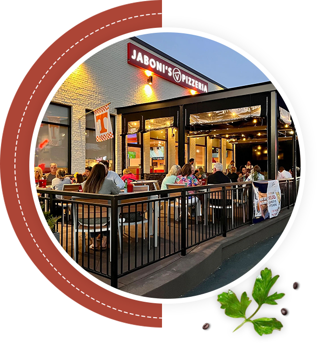 A group of people sitting at tables outside of a restaurant.